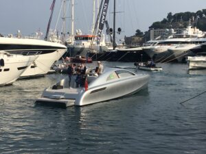 Sleek silver yacht in busy marina.